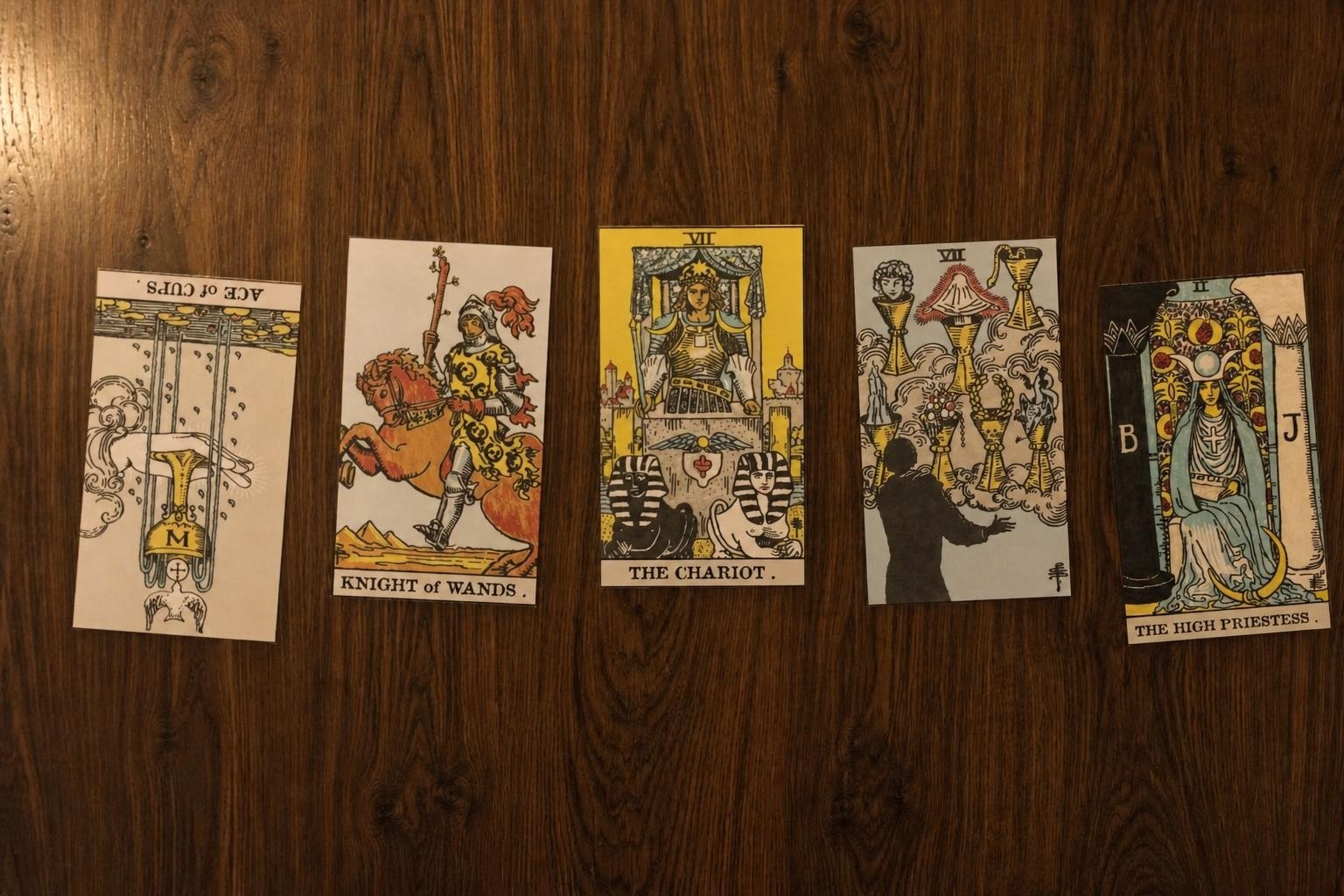 Five physical tarot cards laid out on a wooden table